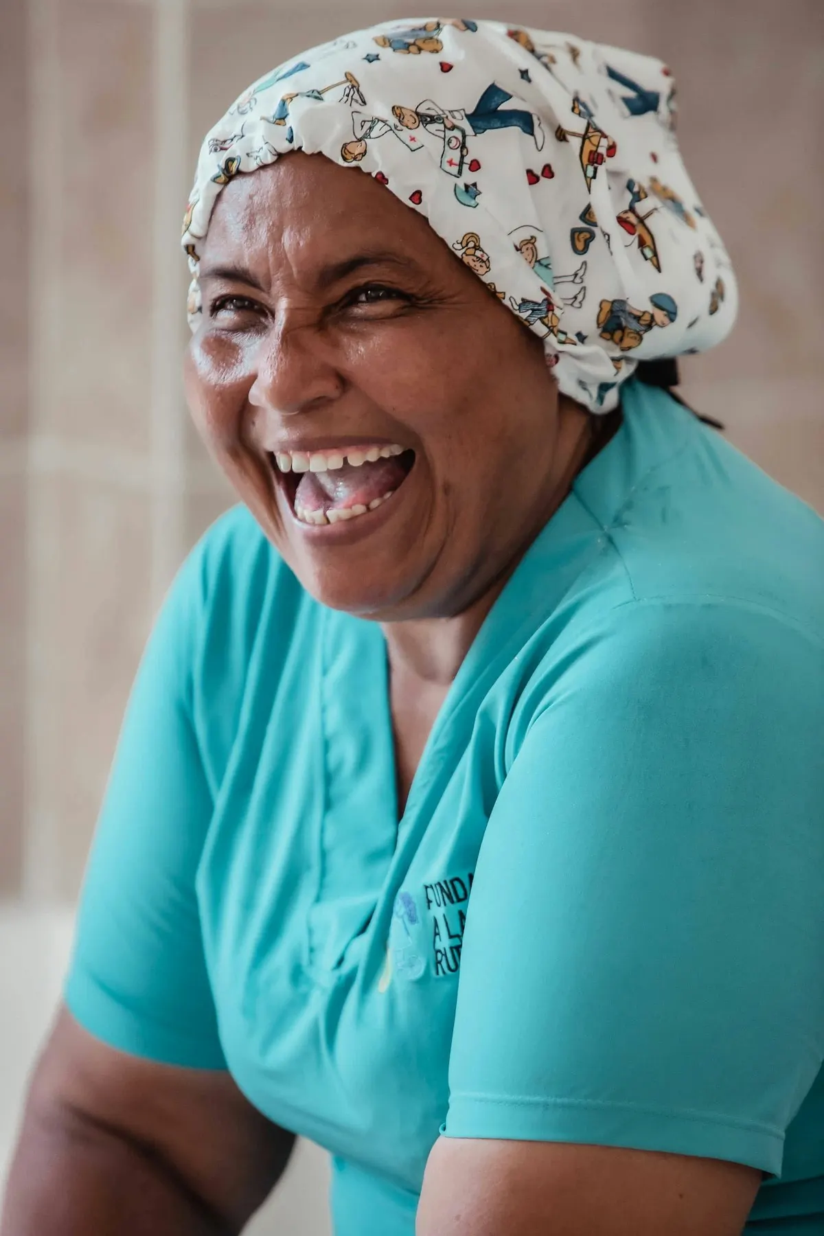 A smiling caregiver in teal scrubs