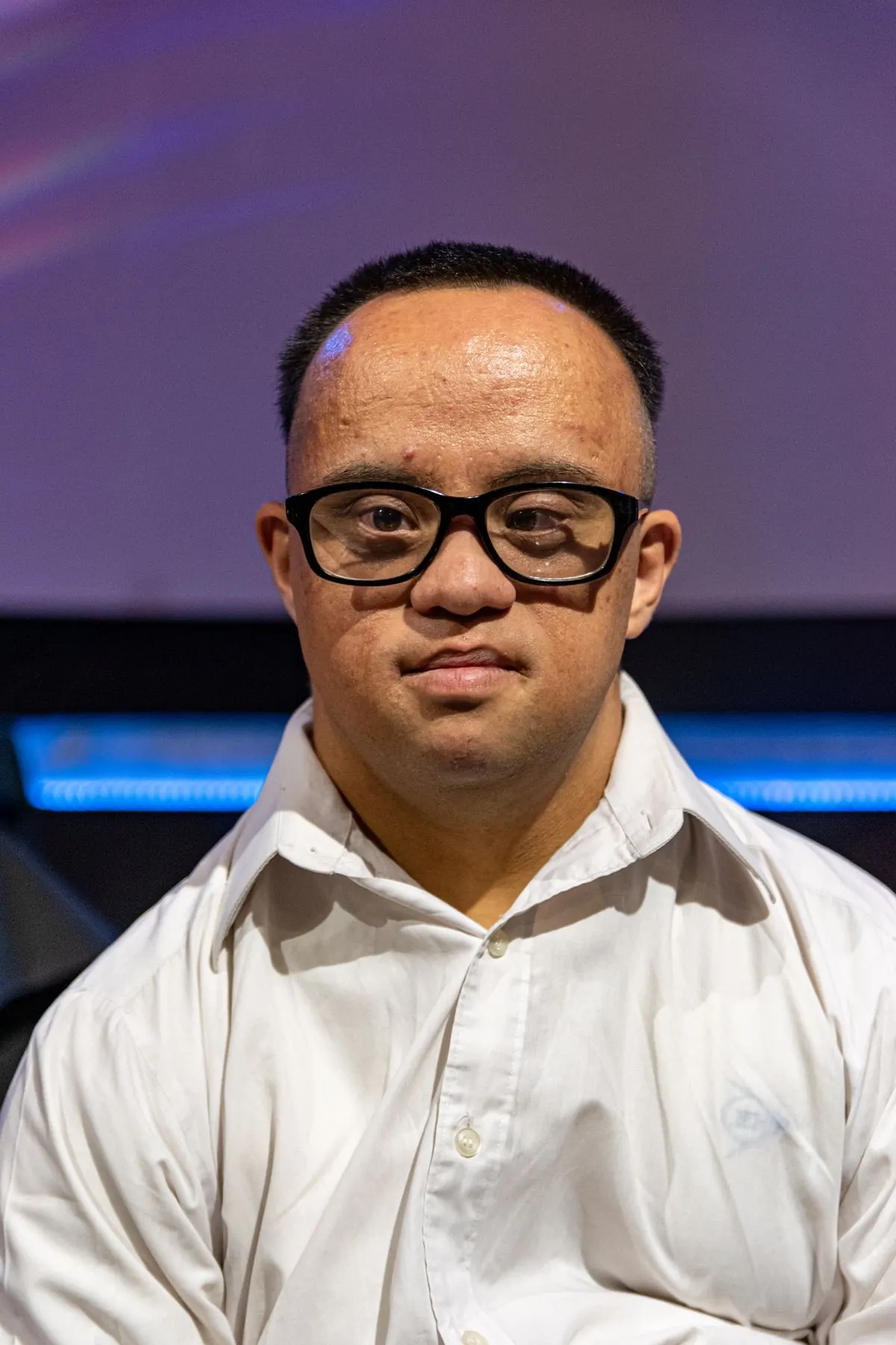 Smiling young man with Down syndrome in a white shirt and glasses