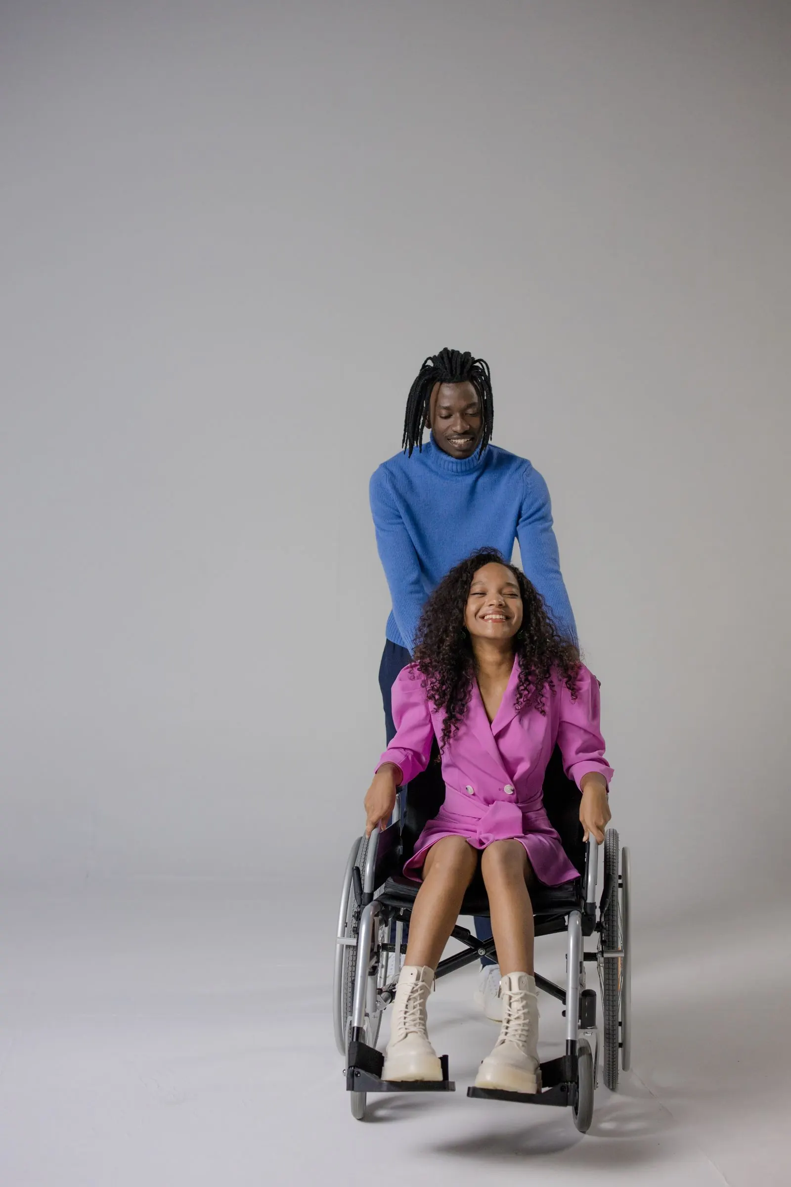A smiling caregiver supporting a young woman who uses a wheelchair
