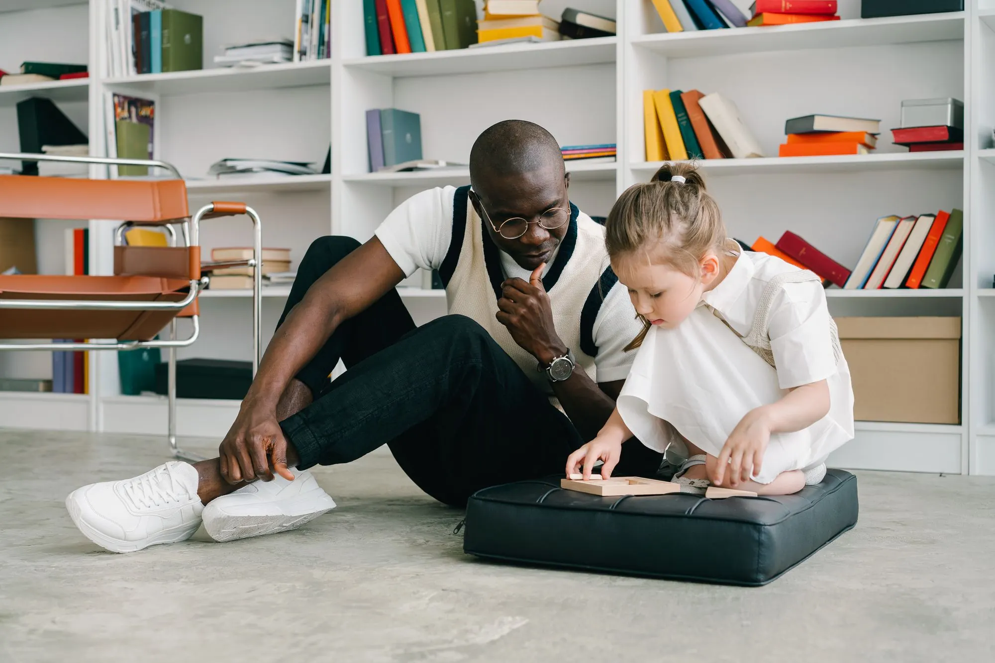 A Jubile Care direct support professional sitting on the floor with a young person, working on an activity together