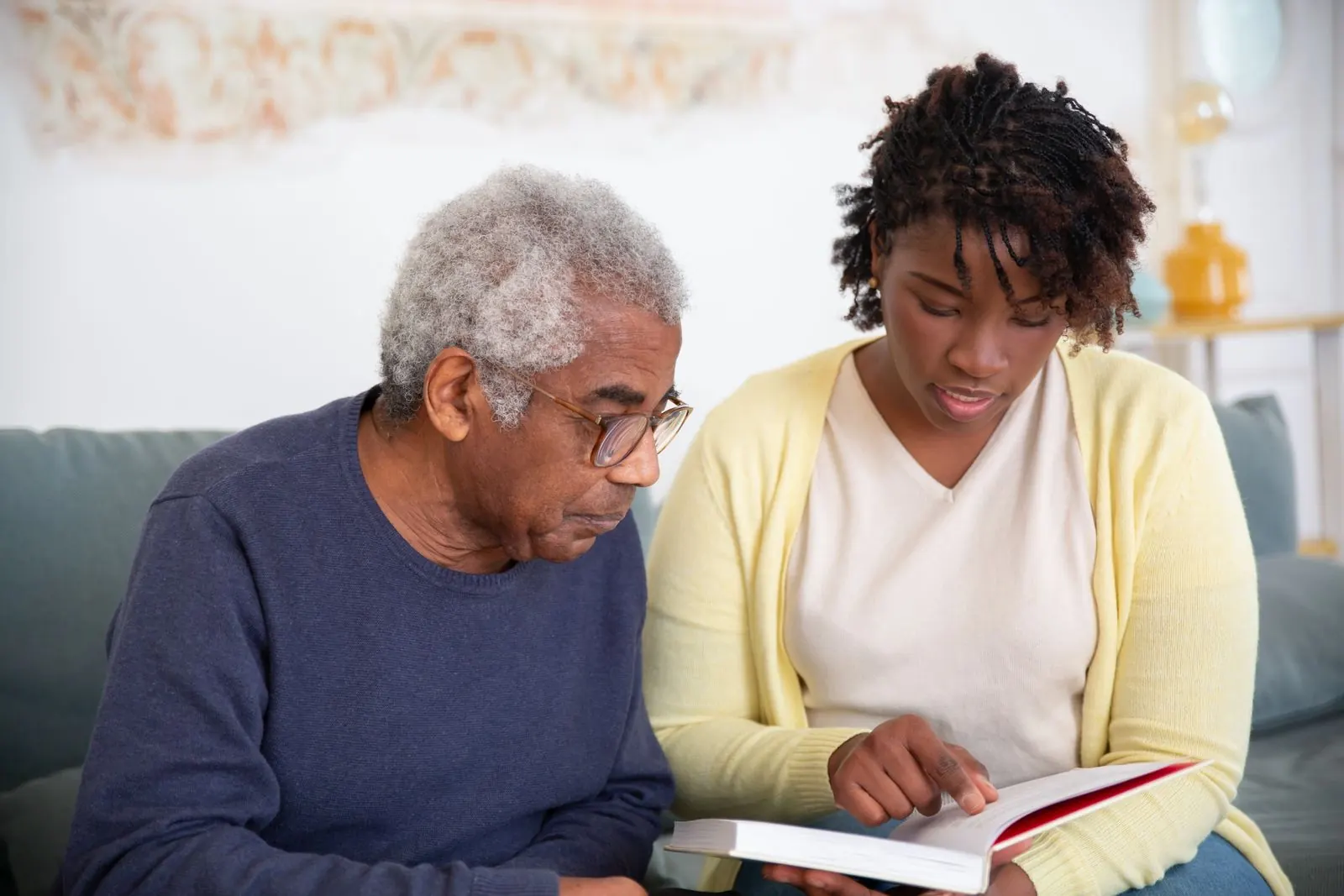 A caregiver reading with an older man at home